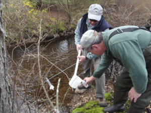 Water quality monitoring volunteers collect a water sample for analysis.